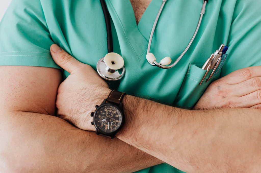 alt="unrecognizable male doctor with stethoscope and arms folded in front."