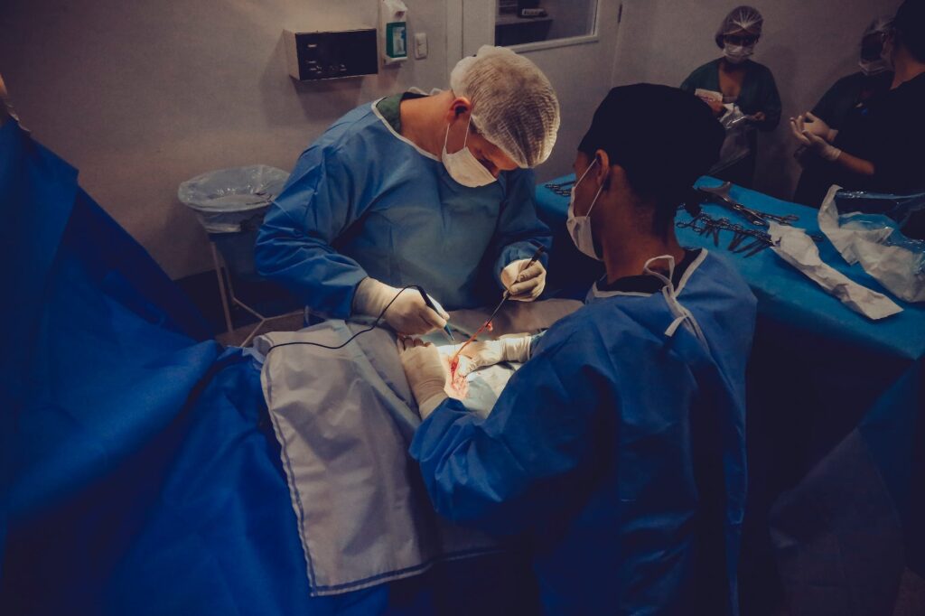 surgeons wearing masks, caps, gowns, and gloves, in an operating room performing surgery on a patient