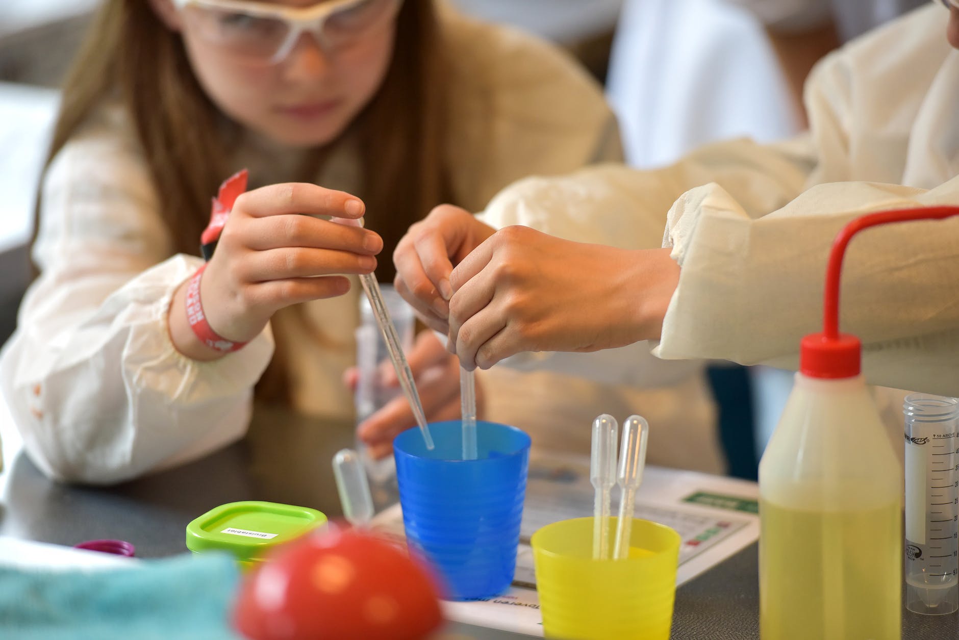 girl with safety glasses holding a pipette on a science experiment