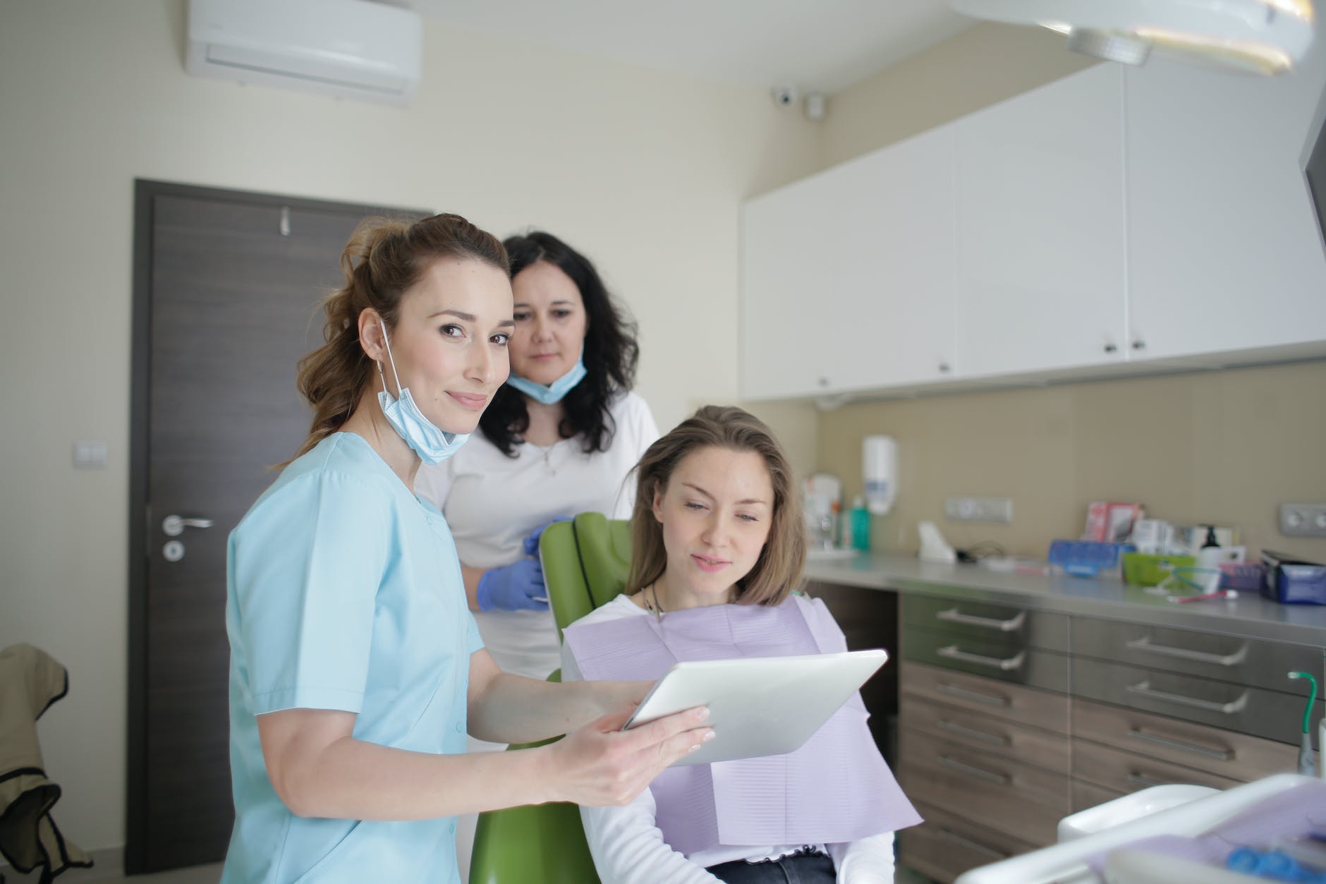 cheerful stomatologist and assistant showing medical report to patient