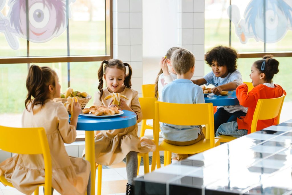 children seated at tables in a cafeteria eating