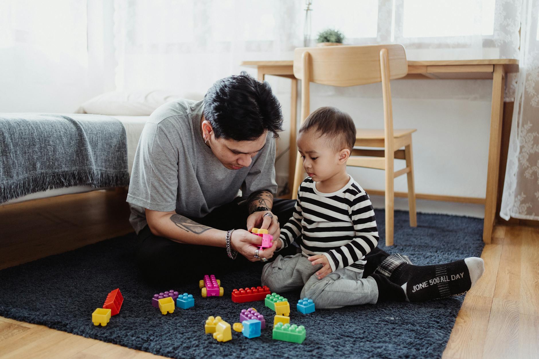 man playing with building blocks with baby boy on a carpet