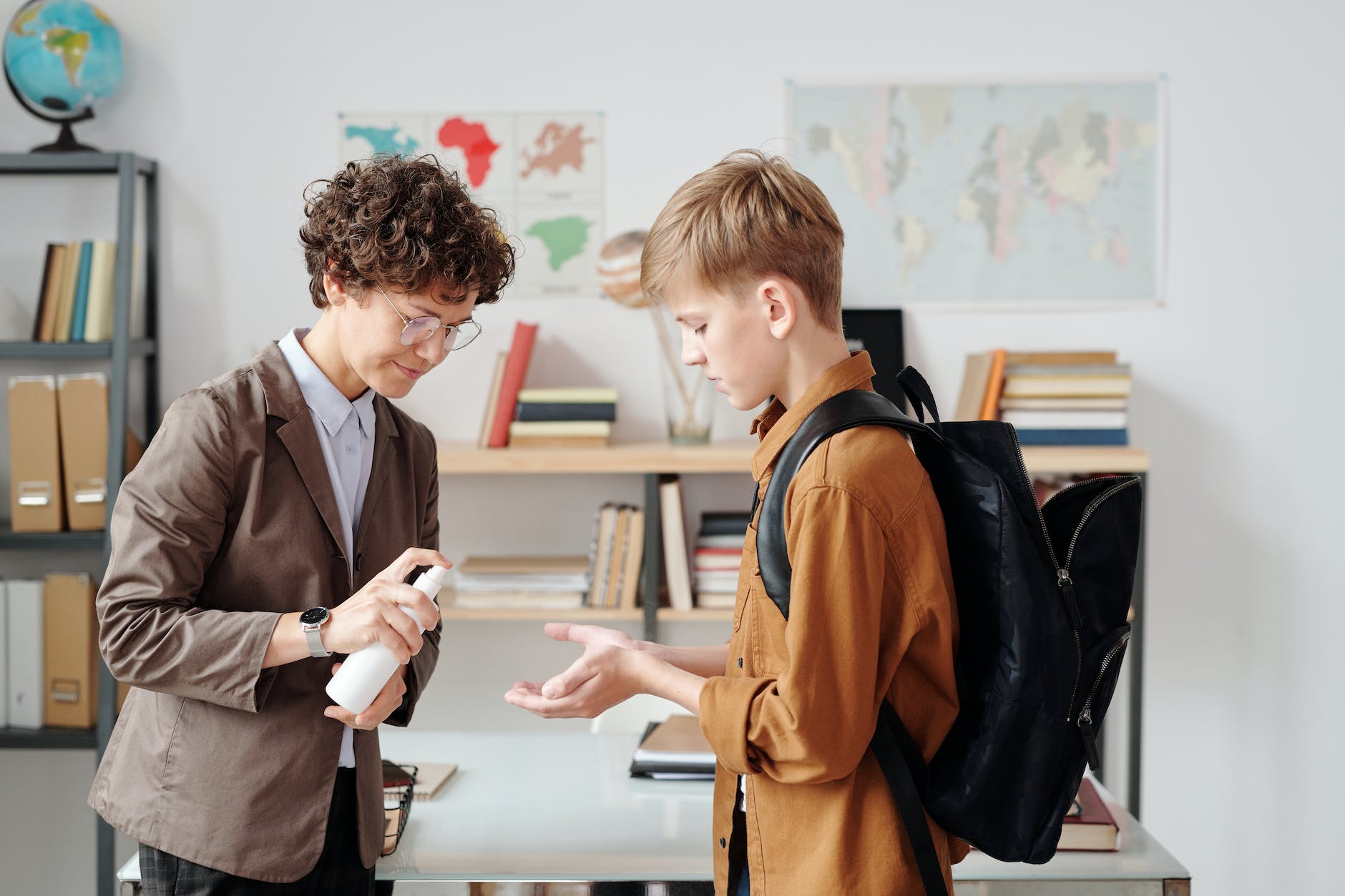 a teacher and boy using hand sanitizer