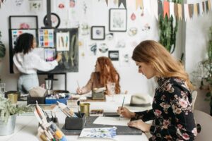 women painting in a room with many images affixed to the walls